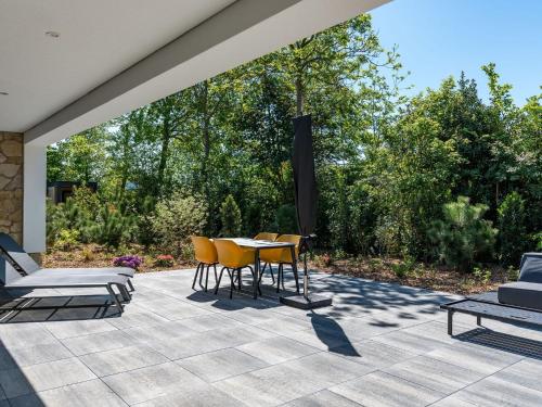 a patio with a table and chairs and trees at Energy neutral villa with wellness area in Den Burg