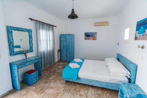 a bedroom with a blue bed and a mirror at Spiridoula Villa - Santorini Seaside Retreats in Perissa