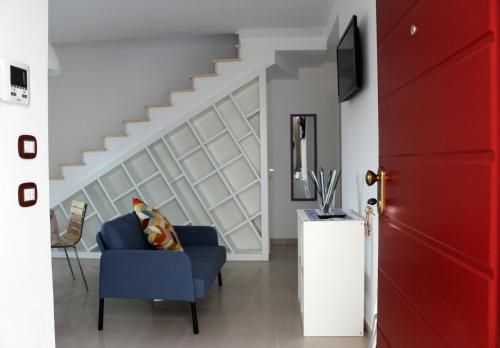 a living room with a blue chair and a staircase at Appartamento “il borgo”, tranquillità e cura a 2 km dal mare in San Vito Chietino