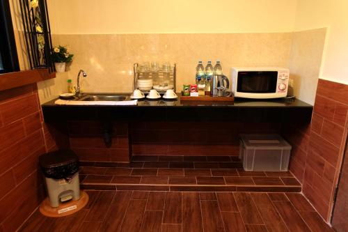 a kitchen with a sink and a microwave on a counter at Namtok Sarika Resotel in Nakhon Nayok