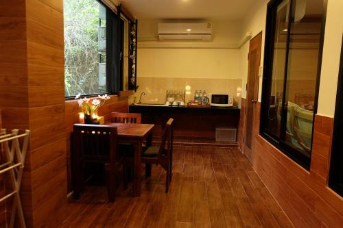 a dining room with a table and a kitchen at Namtok Sarika Resotel in Nakhon Nayok