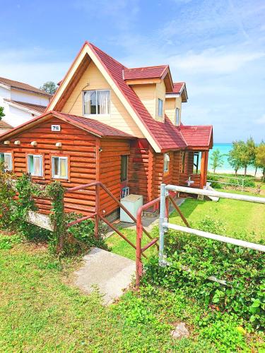 a wooden house with a fence in front of it at Garden Beach House in Motobu