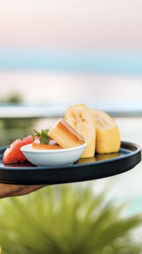 a person holding a plate of food on a tray at Huvan Beach Hotel at Hulhumale in Hulhumale