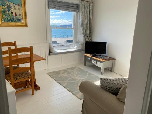 a living room with a couch and a tv and a window at Sophia's in Penzance