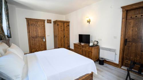 a bedroom with a white bed and a tv at Villa Pietra in Ayvalık