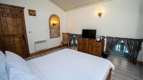 a bedroom with a white bed and a television at Villa Pietra in Ayvalık