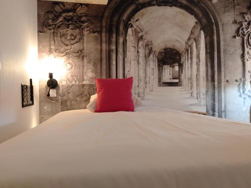 un grande letto bianco con un cuscino rosso di Urban Style Arl HOTEL a Arles