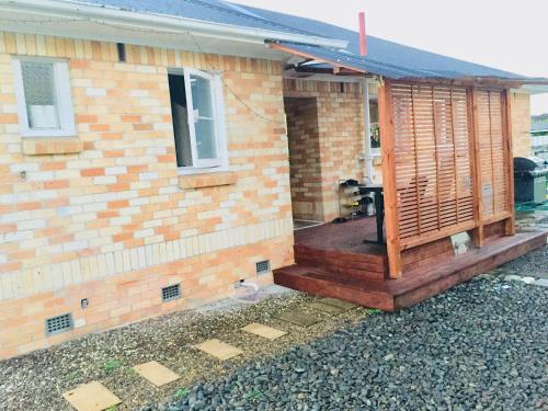 a house with a wooden porch on the side of it at D R Accommodation and Cozy Cabins, Hamilton East near to CBD and Waikato Hospital in Hamilton