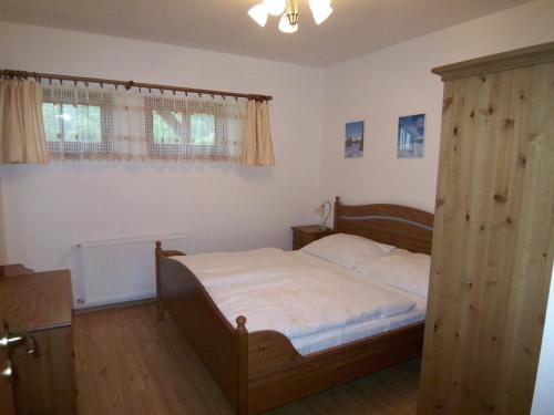 sypialnia z łóżkiem i drewnianą szafką w obiekcie Apartmány U Lanovky w Rokitnicach nad Izerą