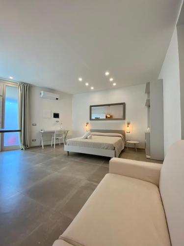 a white bedroom with two beds and a couch at Enjoy Olbia in Olbia
