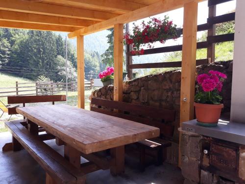 einen hölzernen Picknicktisch auf einer Terrasse mit Blumen in der Unterkunft La quiete di Tregiovo - CIPAT 22253-AT-34903 in Revò