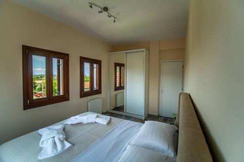 a bedroom with a bed in a room with windows at Villa Clairy in Argalasti, Pelion in Argalasti