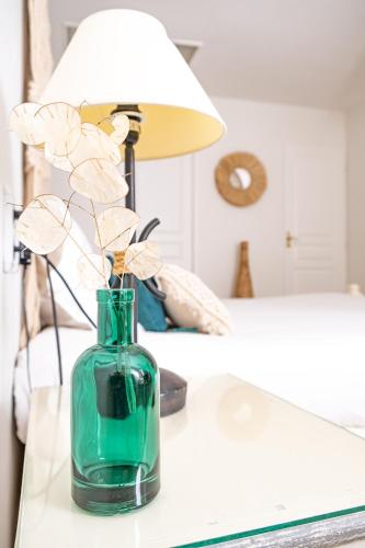 a green vase sitting on a table with a lamp at Logis hôtel et restaurant La Bastide Cabezac in Bize-Minervois