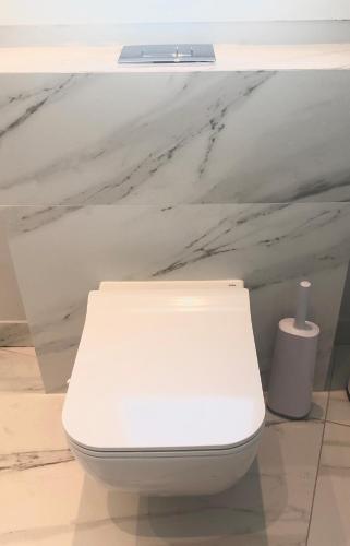 a white toilet in a bathroom with a marble wall at Angel Suites in Nicosia