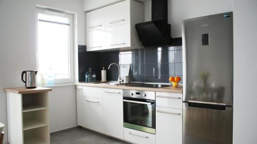 a kitchen with white cabinets and a stove top oven at Apartament Imagus Oliwa in Gdańsk