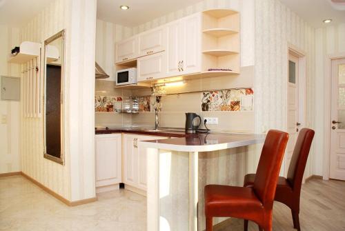 a kitchen with white cabinets and a table and chairs at Apartments with Dnipro view in Kyiv