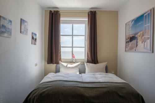a bed in a room with a window at AKZENT Strandhotels Seestern, Delphin & Lachs in Wilhelmshaven
