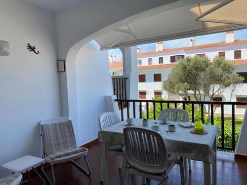 a dining room with a table and chairs and a balcony at Siestamar in Cala en Porter