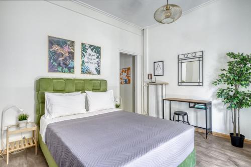 een slaapkamer met een bed met een groen hoofdeinde en een tafel bij Studio in The Heart of Acropolis in Athene