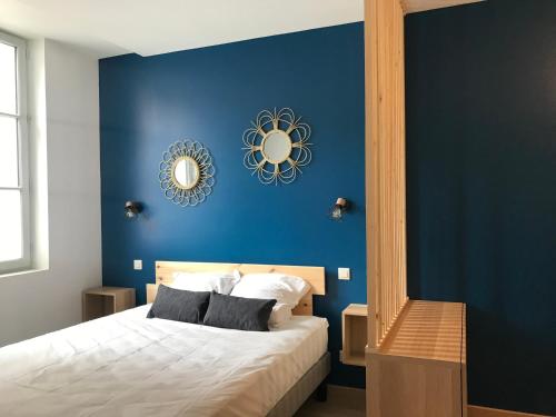 een slaapkamer met een blauwe muur met een bed en een spiegel bij Riva Lodge in Saint-Aignan