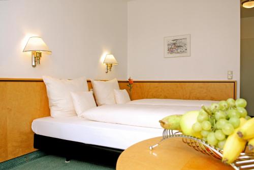 a hotel room with a bed and a table with a basket of fruit at Matchpoint Hotel in Altdorf bei Nuernberg