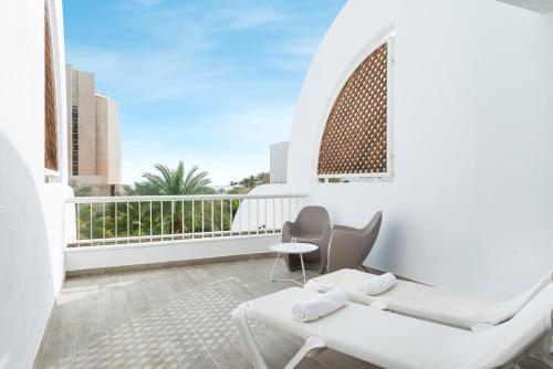 a balcony with white furniture and a view of a building at Sport Club by Isrotel Collection in Eilat
