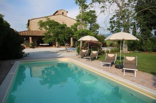 een zwembad met stoelen en parasols naast een huis bij Podere Campo alle Serpi in Bibbona