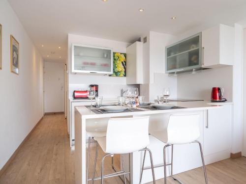 Apartment Ur Gaina-3 by Interhome في بيدار: مطبخ به دواليب بيضاء و كراسي بار بيضاء