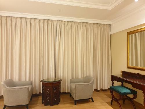 a room with a piano and two chairs and a mirror at ALYA Hotel in Barka