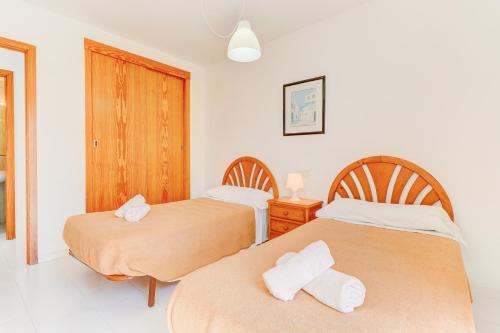1 dormitorio con 2 camas y toallas en Apartamentos Llevant, en Puerto Pollensa