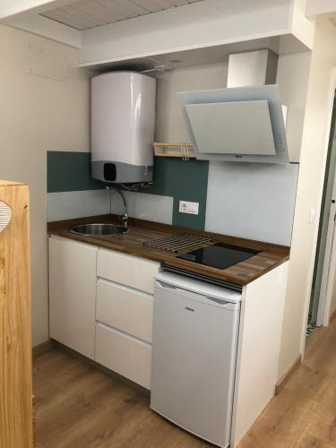 a small kitchen with white cabinets and a sink at Apartamento completamente equipado en Pontedeume. in Puentedeume