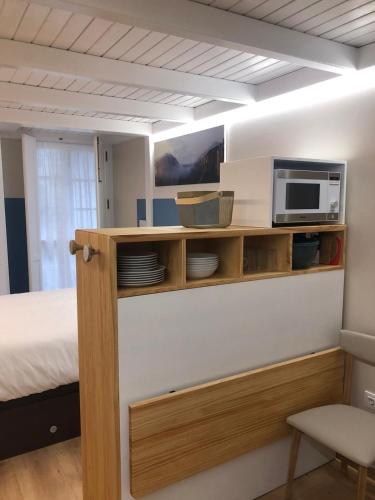 a room with a bed and a microwave on a shelf at Apartamento completamente equipado en Pontedeume. in Puentedeume