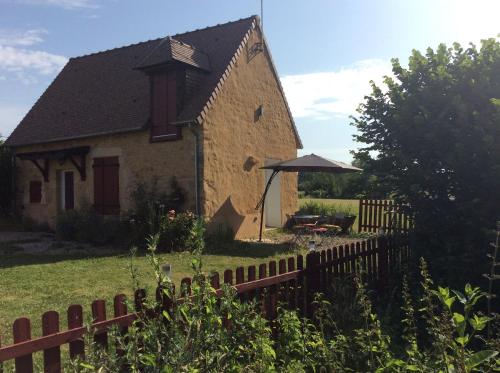 una casa antigua con una valla de madera delante de ella en La Maison entièrement équipée - Boulangerie, en Saint-Pierre-les-Étieux