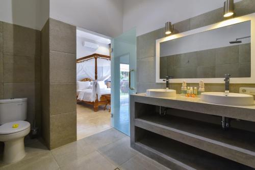 Un baño con dos lavabos y un espejo grande. en Villa Duyung, en Buleleng