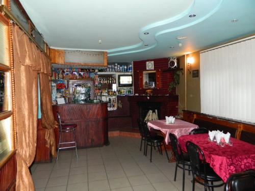 ein Esszimmer mit 2 Tischen und einer Bar in der Unterkunft Готель АРГО in Khrystynivka