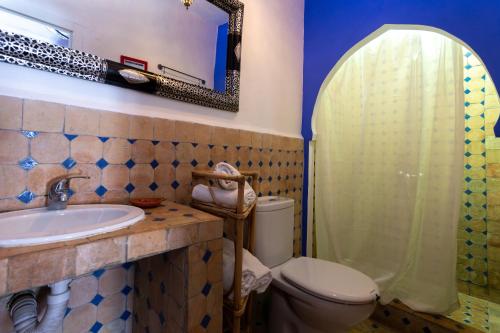 a bathroom with a toilet and a sink and a mirror at Hotel Casa Miguel in Chefchaouene