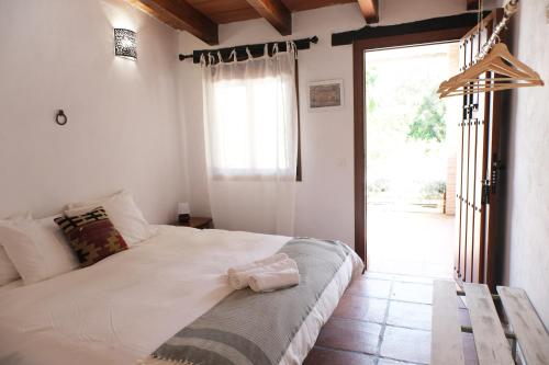 Un dormitorio con una gran cama blanca y una ventana en The Wild Olive Andalucía Citrus Suite, en Casares