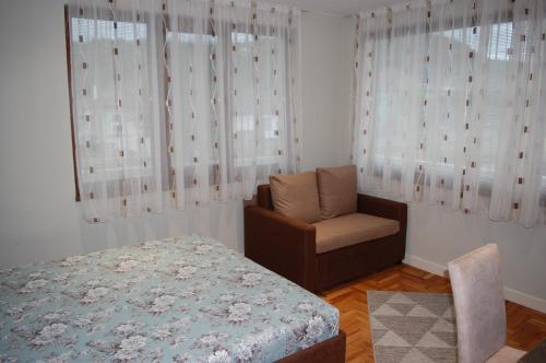 um quarto com uma cama, uma cadeira e uma janela em Апартамент Здравец em Tryavna