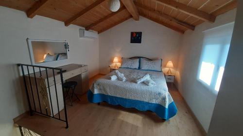 una camera da letto con un letto, una scrivania e uno specchio di White Manolia Cottage a Kato Korakiana