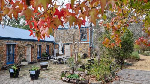 a brick house with a patio and a tree at Barossa Valley Springton Cottages in Springton