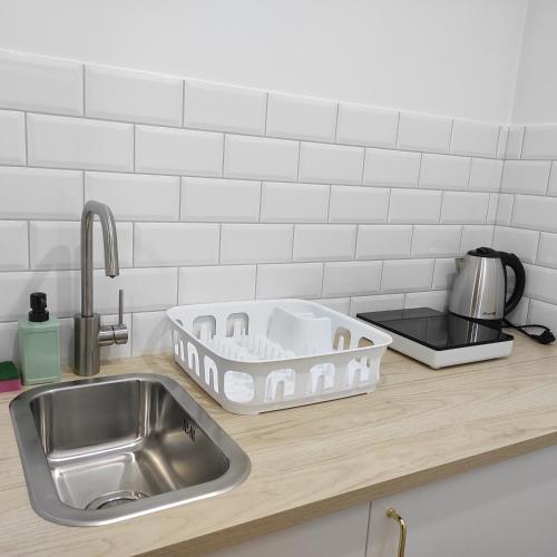 a kitchen counter with a sink and a dish drying rack at Domek w Parku Hel in Hel