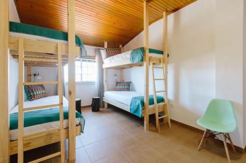 ナザレにあるZulla Nazaré`s Surf Villageの二段ベッド2台と椅子が備わる客室です。