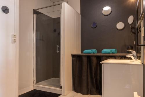 prysznic ze szklanymi drzwiami obok umywalki w obiekcie Albert Goupil - LAVALOC w mieście Laval