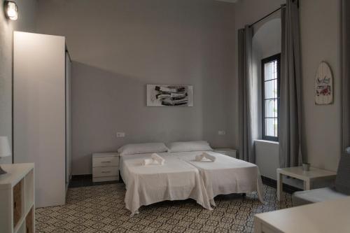 a white bedroom with a bed and a window at Factory Rooms Barbate in Barbate