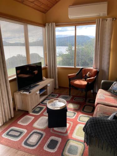 a living room with a tv and a large window at The Boat Shed in Sandford