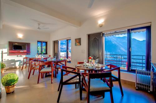 uma sala de jantar com mesas e cadeiras e janelas grandes em Rosewood Retreat Bhimtal em Bhimtal