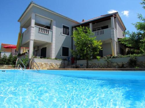 a villa with a swimming pool in front of a house at Villa with garden and pool Supetar Island Brac in Supetar