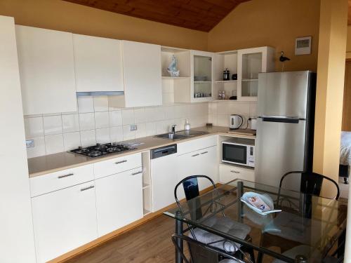 Una cocina con gabinetes blancos y una mesa de vidrio. en The Boat Shed, en Sandford