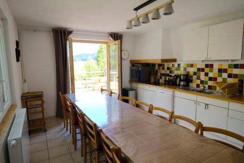 une cuisine avec une grande table et des chaises en bois dans l'établissement Gite des Rosiers, à Lans-en-Vercors