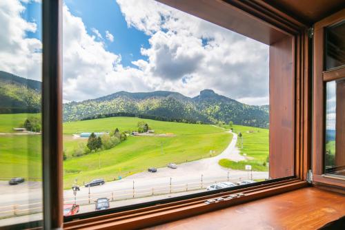 a window with a view of a road and mountains at Salaš Syrex in Zázrivá